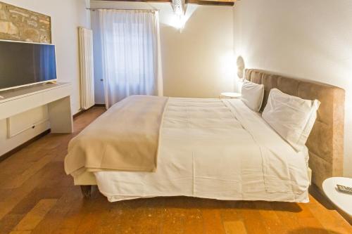 a bedroom with a large white bed with a flat screen tv at Locanda Del Feudo Suite & Restaurant in Castelvetro di Modena
