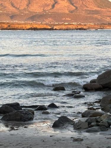 a beach with rocks and a body of water at Primavera y dias de sol en Cabaña Roscoe's Paradise Playa Los Molles- 2 -3 personas in Los Molles