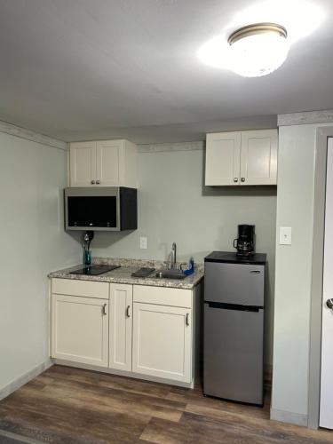 eine Küche mit weißen Schränken, einer Spüle und einem Kühlschrank in der Unterkunft Boulevard Motel in Marmora