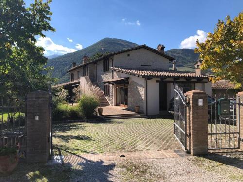 a house with a gate and a mountain in the background at Casa Vinto in Cagli