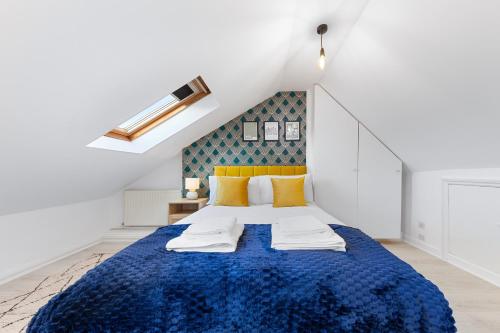 Un dormitorio con una cama azul con almohadas amarillas en The Holloway Suite - 1BR Modern Apartment en Londres