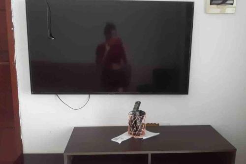 a television on a wall with a bottle on a table at Casa da Cascata de Crato in Crato