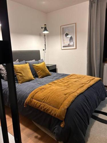 une chambre avec un lit avec des oreillers jaunes dans l'établissement Élégant F2 luxueux proche Suisse, à Delle