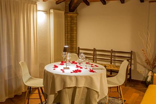 a table with a white table cloth and red flowers on it at Locanda Del Feudo Suite & Restaurant in Castelvetro di Modena