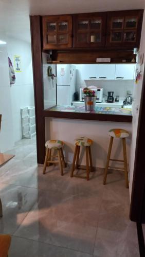 a kitchen with a counter and two stools in it at Casa de 3 Quartos em Garopaba - Bairro Ferraz in Garopaba