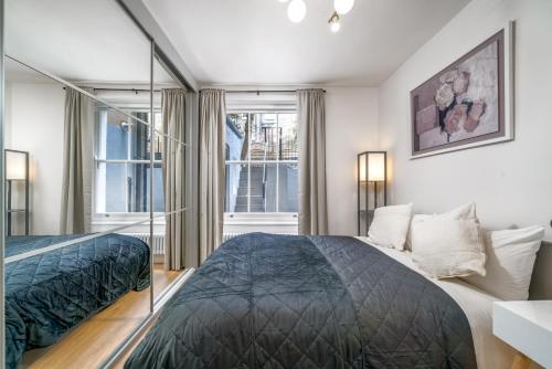 een slaapkamer met een bed en een groot raam bij NIRU Experience Urban Escape 1BR Retreat in Londen