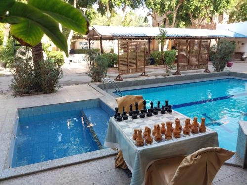 a table with a chess board next to a swimming pool at Rezeiky Hotel & Camp in Luxor
