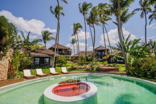 a pool at a resort with palm trees at Jaya Pousada Boutique in São Miguel do Gostoso