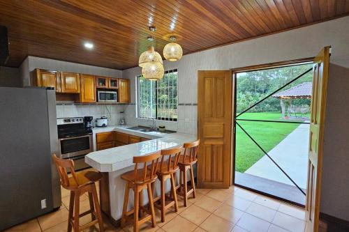 a kitchen with a table and chairs and a large window at Casa Roble Fortuna in Fortuna