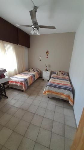 1 dormitorio con 2 camas y ventilador de techo en Doña Rita departamentos en Villa María