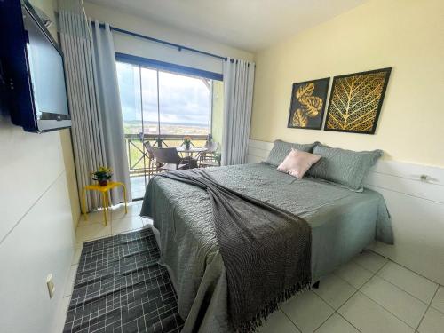 a bedroom with a bed with a view of a balcony at Hotel Fazenda Monte Castelo Flat Gravatá in Bezerros