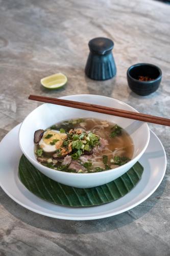 a bowl of soup with chopsticks on a plate at Chic stay HANA Boutique hotel in Luang Prabang
