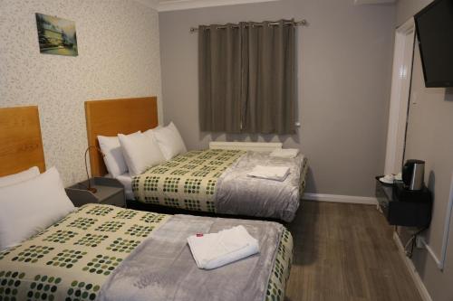 a hotel room with two beds and a window at Elstree Inn in Borehamwood