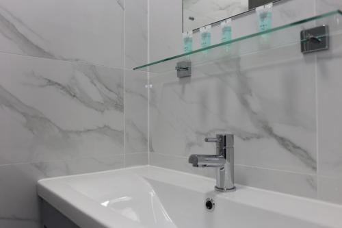 Baño blanco con lavabo y espejo en Elstree Inn, en Borehamwood