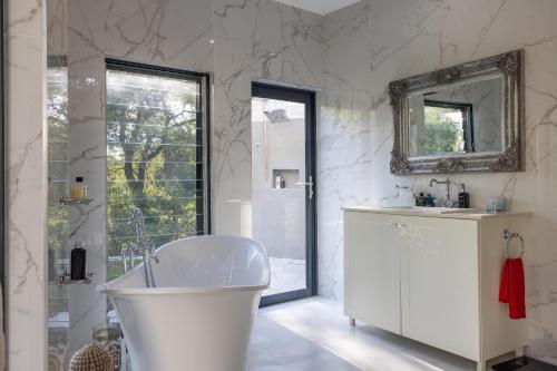 a white bathroom with a tub and a mirror at Oase by 7 Star Lodges - Greater Kruger Private 530ha Reserve in Hoedspruit