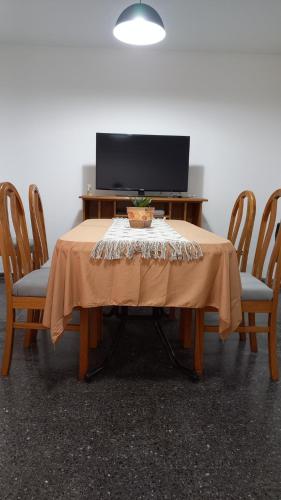 a table with a television and a table with chairs at Sueños del Pilar in Godoy Cruz