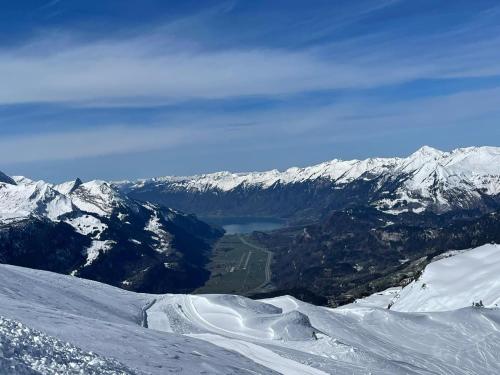 a view of a snow covered mountain with a lake at Apartment HasliView in Innertkirchen