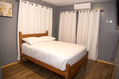 a bedroom with a bed with white sheets and curtains at Avalon Regia 2 Bathroom Downstairs Apartment in Georgetown