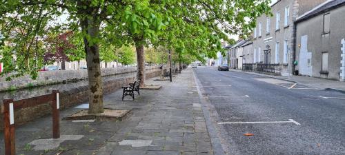 a tree lined street with benches and buildings at Central Westport Town House in Westport