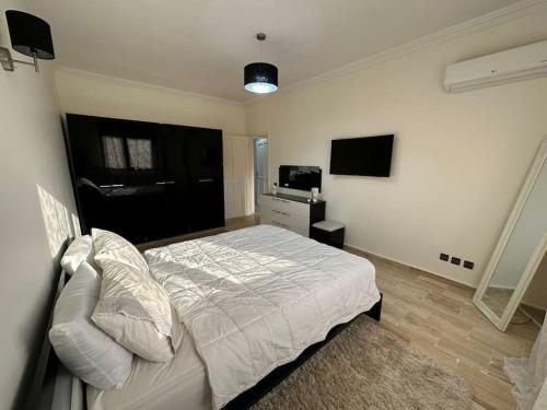 una camera con letto bianco e TV di Luxury, Cosy Apartement (Wifi, Balcony, Parking) a Marrakech