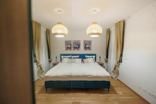a bedroom with a blue bed and two pendant lights at Zoder Apartments in Vienna
