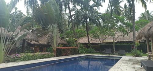 a swimming pool in a resort with palm trees at Mama Bella's Retreat in Senggigi 