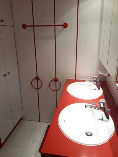 ein Badezimmer mit zwei Waschbecken und einer roten Theke in der Unterkunft Balcon plein Sud sur les pistes in Isola 2000