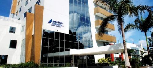 un bâtiment avec un palmier en face dans l'établissement Apto Hotel Blue Tree Manaus, à Manaus