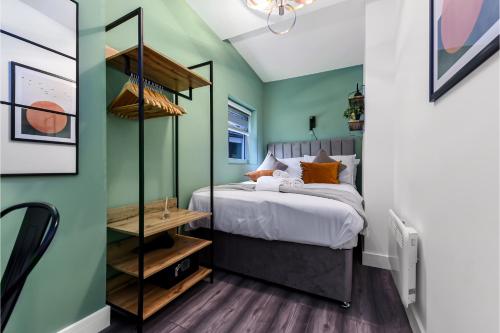 a bedroom with green walls and a bed with orange pillows at Fabulous One Bedroom Flat with Private Garden in London