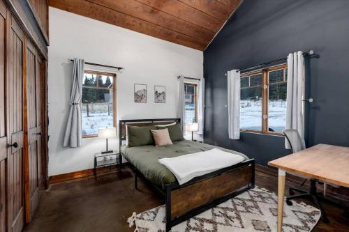 a bedroom with a bed and a table and windows at The Bross Ranch Cabin - Open Floor Plan! 10Mi to Ski Breck! Hot Tub! in Fairplay