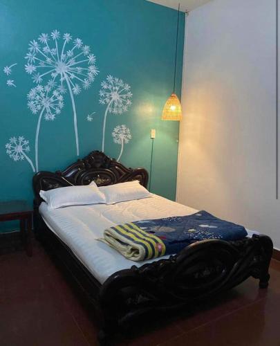 a bedroom with a bed with dandelions painted on the wall at 305HA Gest house in Ninh Binh