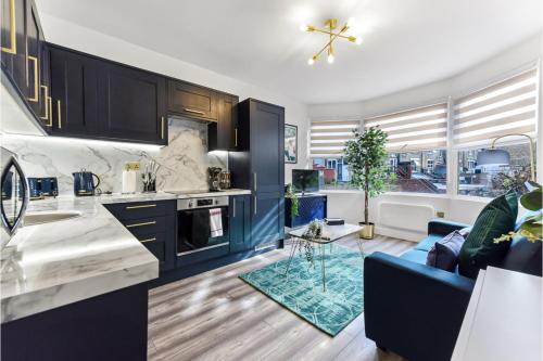 a kitchen with blue cabinets and a blue couch at Stylish and Family Friendly 3 Bedroom Apartment in London