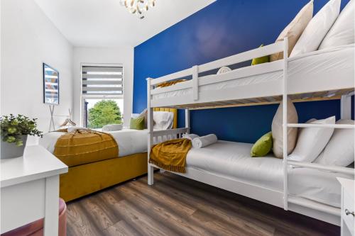 two beds in a room with blue walls and white bunk beds at Stylish and Family Friendly 3 Bedroom Apartment in London