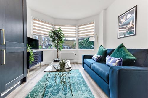 a living room with a blue couch and a table at Stylish and Family Friendly 3 Bedroom Apartment in London