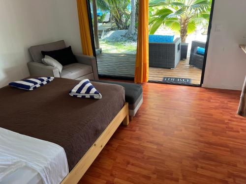 a bedroom with a bed and a chair and a patio at Te Mao in Avatoru