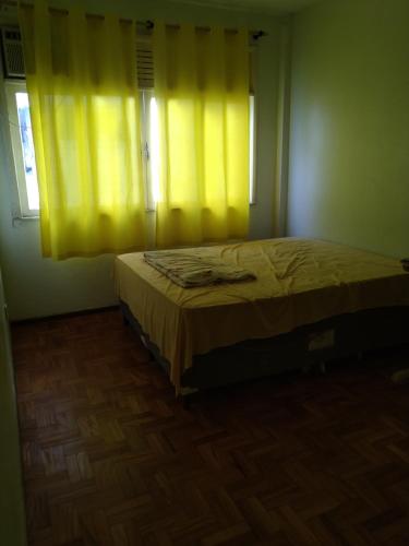 a bedroom with a bed and a window with yellow curtains at Carnaval in Barra in Salvador