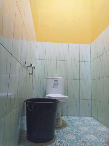 a bathroom with a toilet and a trash can at Penginapan Ana Indah in Borobudur