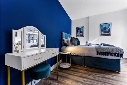 Lovely Two Bedroom with Ensuite Bathrooms في لندن: غرفة نوم بجدران زرقاء وسرير مع مرآة