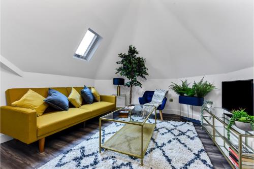 a living room with a yellow couch and blue pillows at Lovely Two Bedroom with Ensuite Bathrooms in London