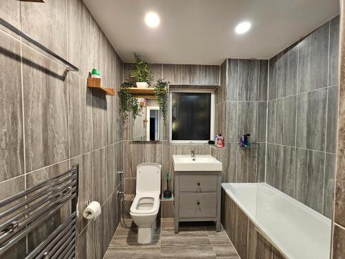 a bathroom with a toilet and a sink and a tub at Wallwood Rooms in London
