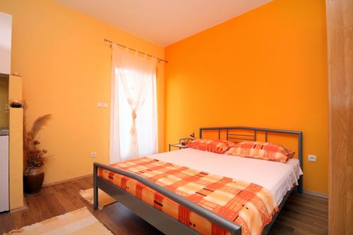 a bedroom with orange walls and a bed and a window at Apartments with a parking space Vrisnik, Hvar - 8733 in Jelsa