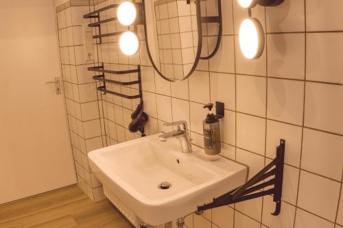 ein Bad mit einem Waschbecken und einem Wandspiegel in der Unterkunft No.1 by 21Apartments in Krefeld