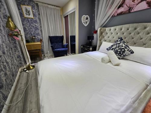 a bedroom with a large white bed and a blue chair at Wallwood Rooms in London