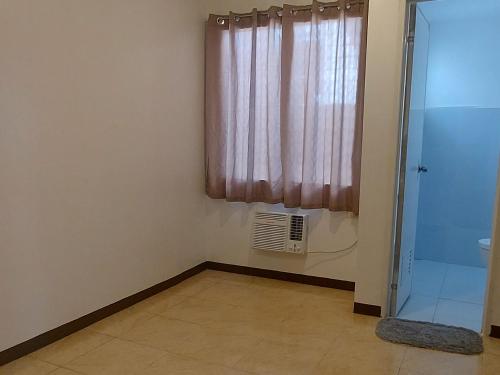 a small room with a window and a shower at Snowbird Townhouse Azumi in Dumaguete