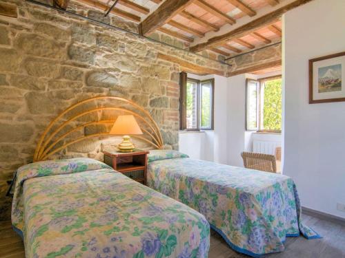a bedroom with two beds and a stone wall at Spacious Holiday Home in Amandola with Swimming Pool in Amandola