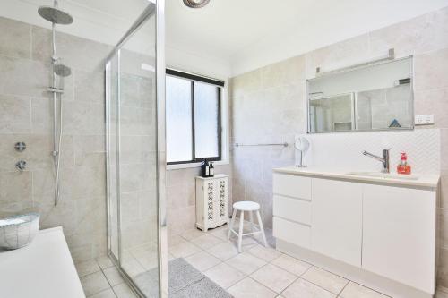 a bathroom with a shower and a sink and a mirror at Annabel's Place - Pet Friendly with Fireplace in Vincentia