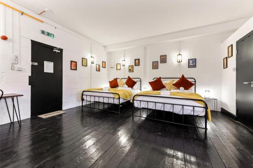 Trendy and Eccentric Flat in Hackney في لندن: سريرين في غرفة بيضاء مع سريرين مطلة على السرير