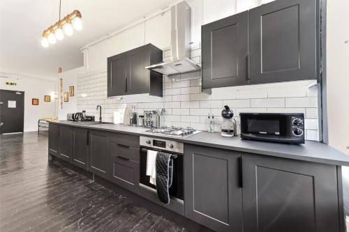 a kitchen with black cabinets and a microwave at Trendy and Eccentric Flat in Hackney in London