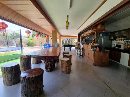 a kitchen with a large wooden table and stools at Pool Villa Kiang Na Mae Rim in Mae Rim