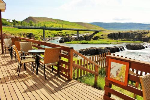 a deck with chairs and a table and a river at Fossatún Sunset Cottage in Fossatún